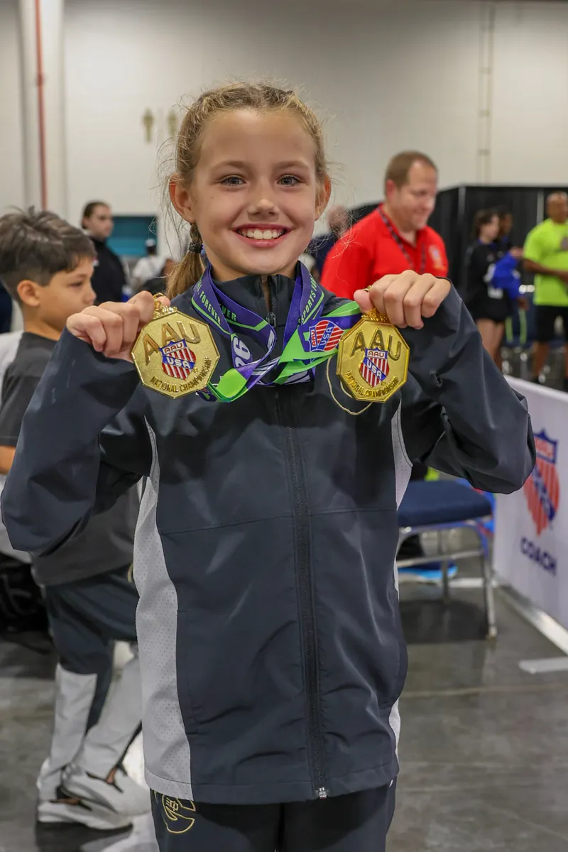 Dominika Tsybina holding two AAU National Championship karate gold medals