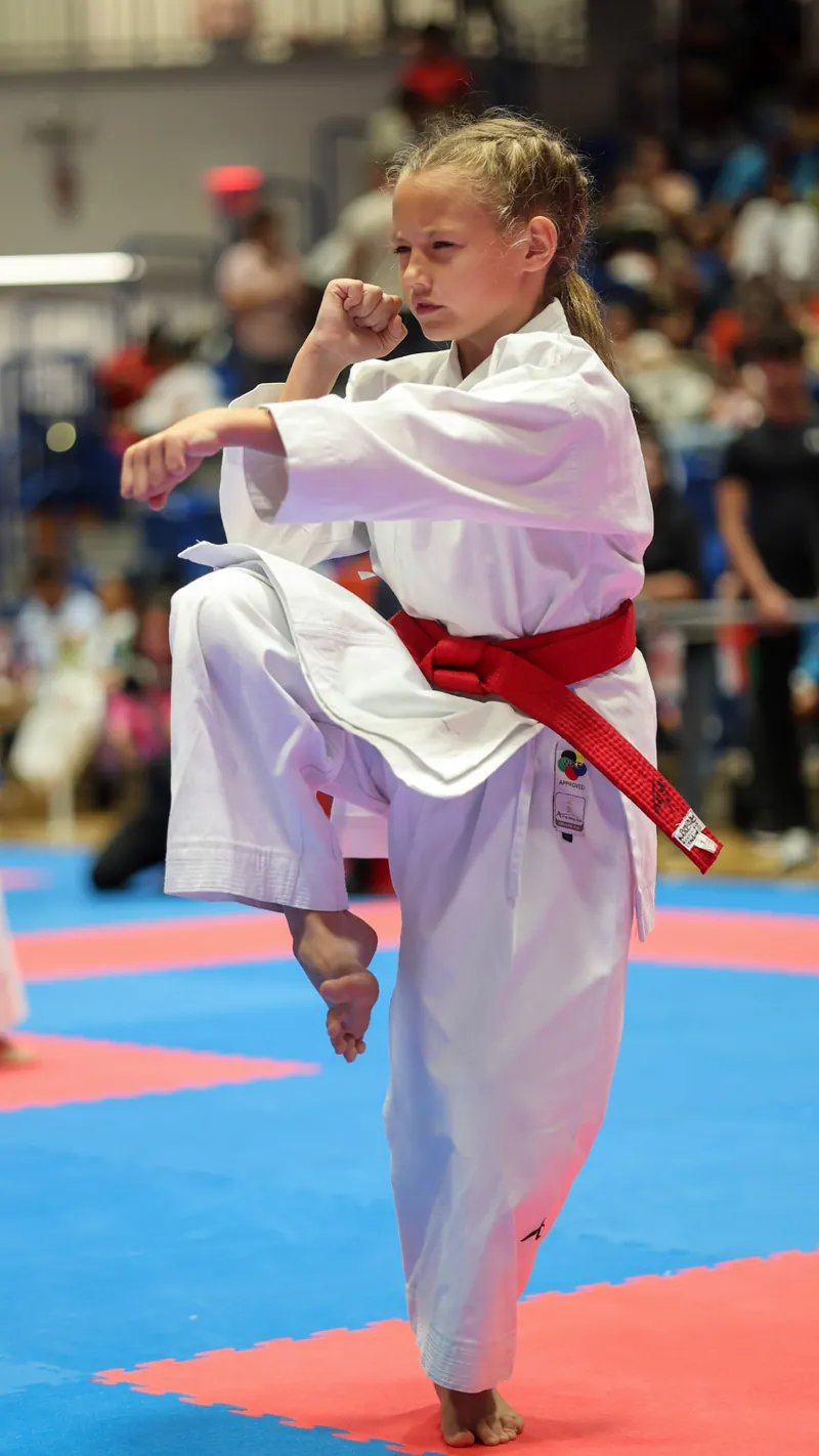 Dominika Tsybina holding a karate kata stance while wearing a red competition belt