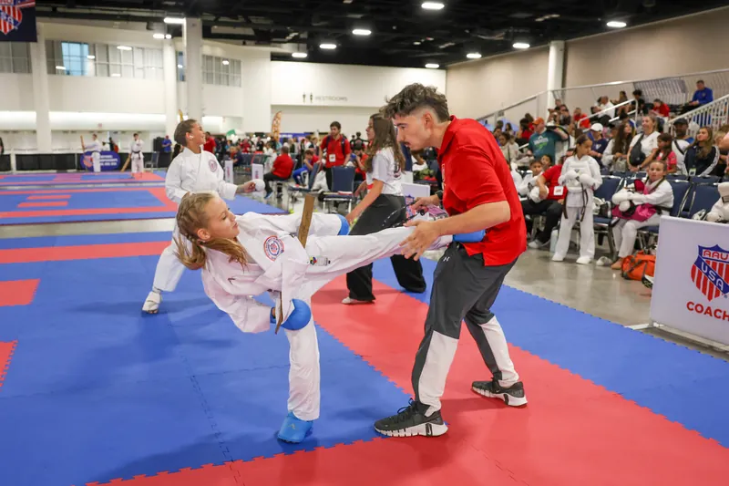 Dominika Tsybina practicing a high karate kick with her coach during training