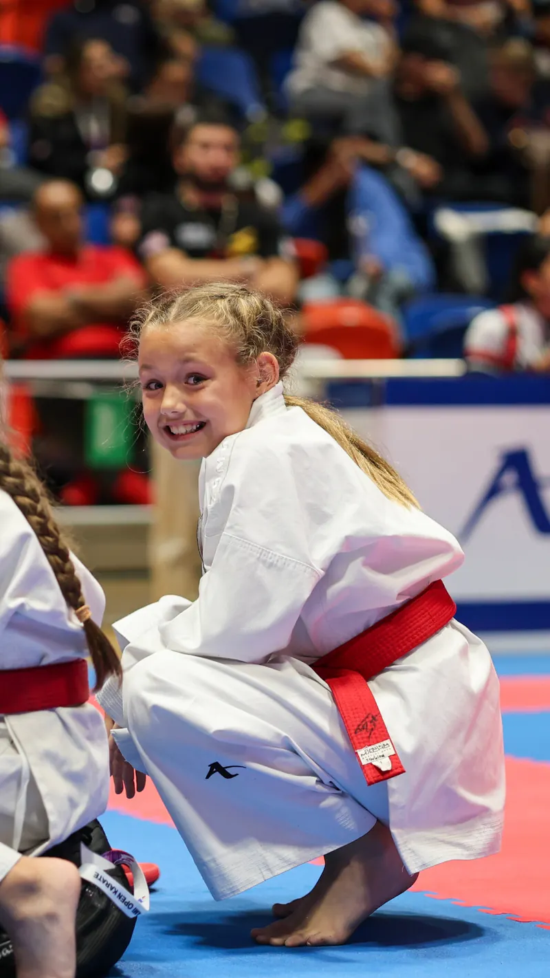 Youth karate athlete Dominika Tsybina smiling on the tatami before her match